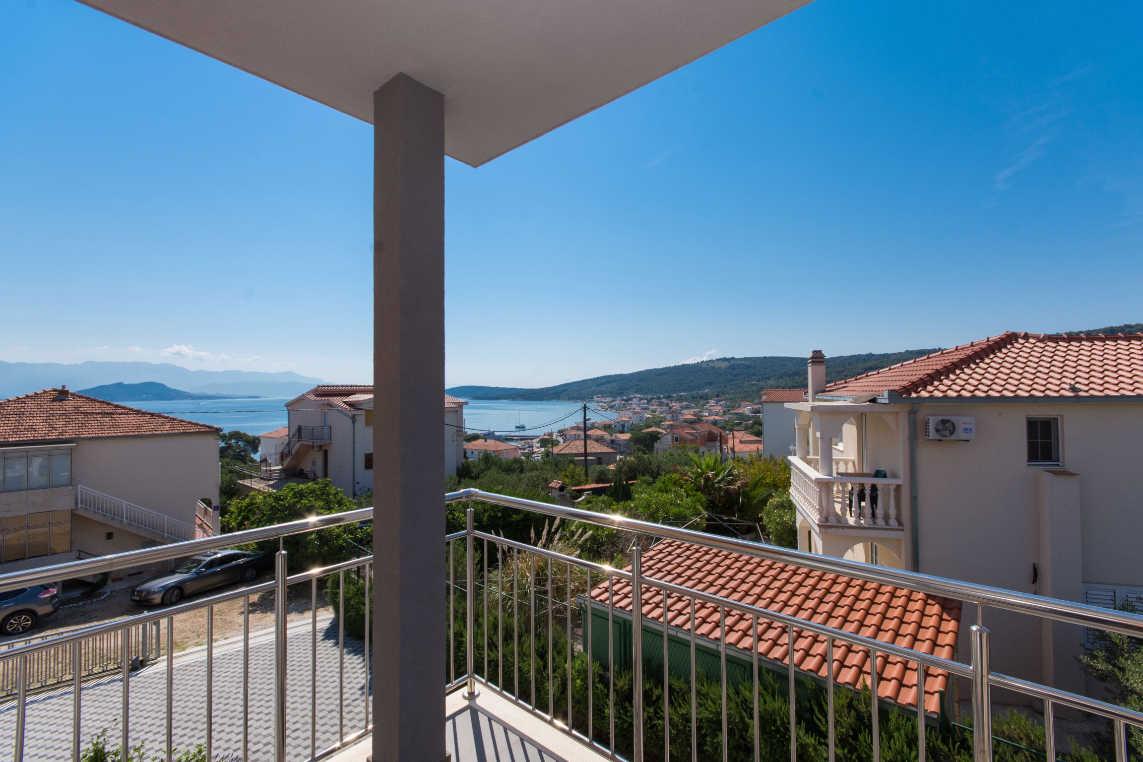 Apartment Sage balcony view — the Adriatic sea framed by terracotta rooftops and cypress